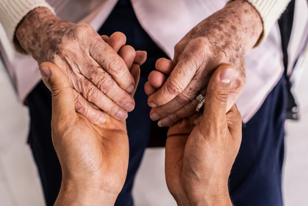 Close-up of a caregiver holding hands senior woman