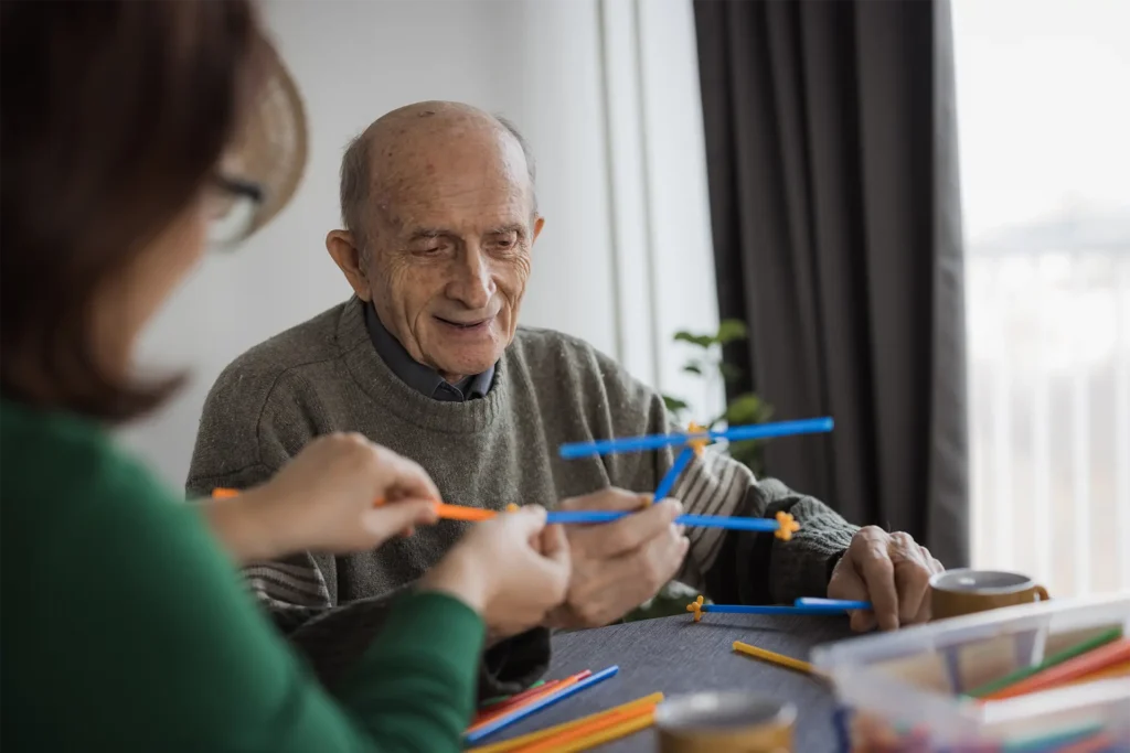 Happy senior man having fun time when playing building straw block set