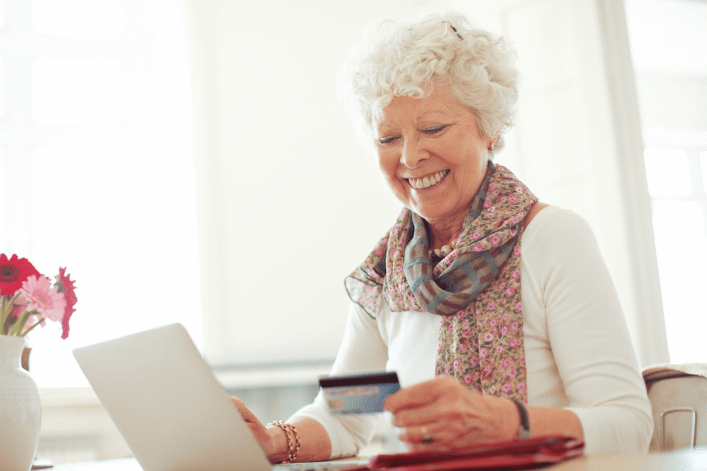 Old woman happy doing her shopping online using a credit card.